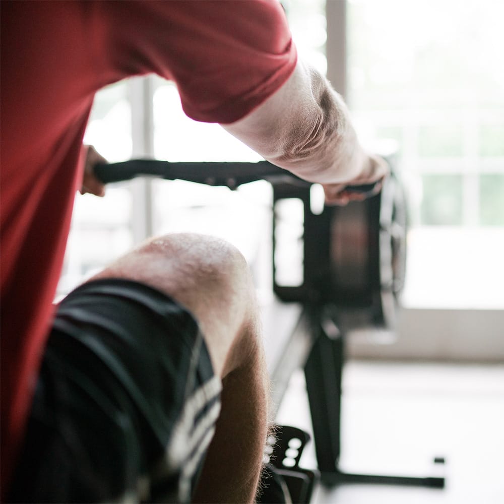 man exercising at the gym with a rowing machine
